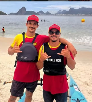 Gabriel Mattos e Rodrigo Fernandez de colete na areia, com o Pão de Açúcar ao fundo